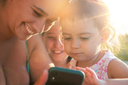 Girls looking at a phone outdoors at sunsetの写真素材