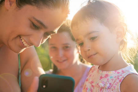 Girls looking at a phone outdoors at sunsetの写真素材