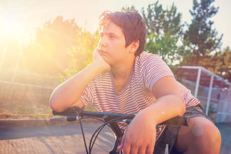 Boy posing in a bicycle outdoors at sunsetの写真素材