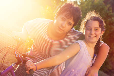 Happy young kids couple outdoors at sunset with bicycleの写真素材