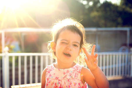 Sweet young girl making faces outdoors at sunsetの写真素材