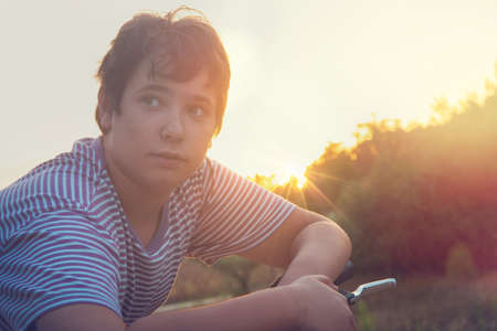 Boy posing in a bicycle outdoors at sunsetの写真素材