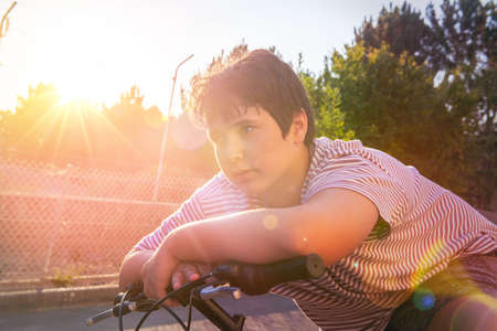 Boy posing in a bicycle outdoors at sunsetの写真素材