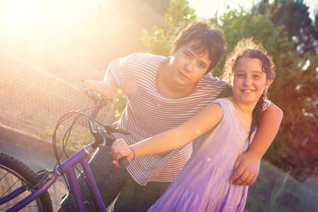 Happy young kidâs couple outdoors at sunset with bicycleの写真素材