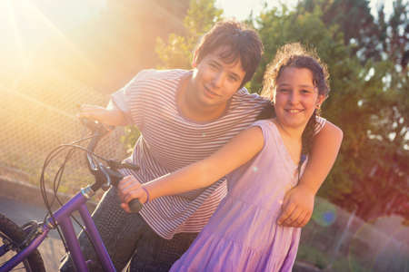 Happy young kidâs couple outdoors at sunset with bicycleの写真素材