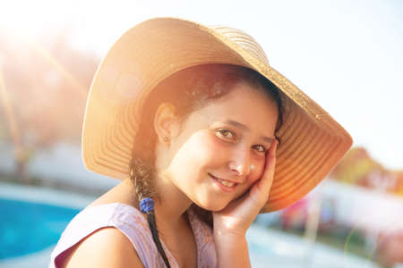 Sweet young girl posing with hat outdoors at sunsetの写真素材