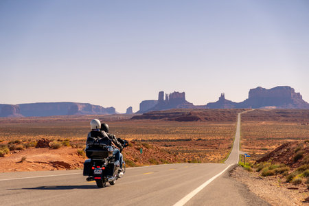 Unrecognizable Couple on Motorcycle at Monument Valley Forest Gump Point down a long, empty road...