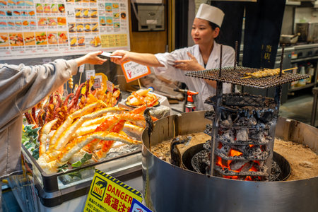 Osaka, Japan - November 4, 2025: Woman Chef Serving at Grilled Seafood in Osaka Kuromon Marketのeditorial素材