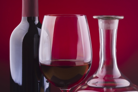 Glass and bottle of wine over red backgroundの写真素材