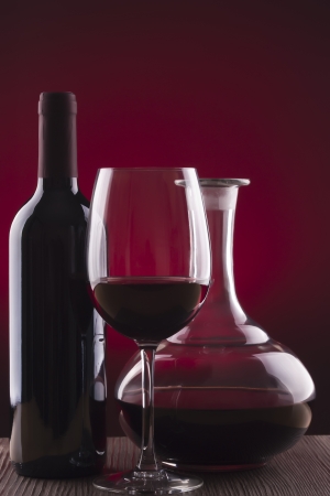 Glass and bottle of wine over red backgroundの写真素材