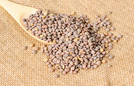 lentils in a wooden spoon on a sack clothの写真素材