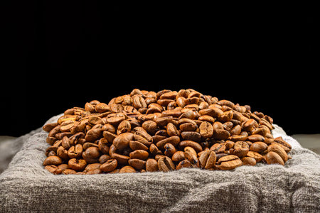 coffee beans on sackcloth isolated on black background with copy space