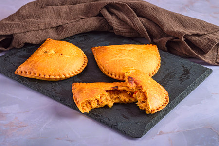 Freshly baked empanadas on rustic stone board