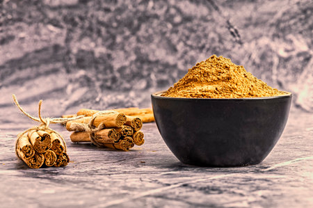 Cinnamon sticks and powder in a bowl on a gray background.の写真素材