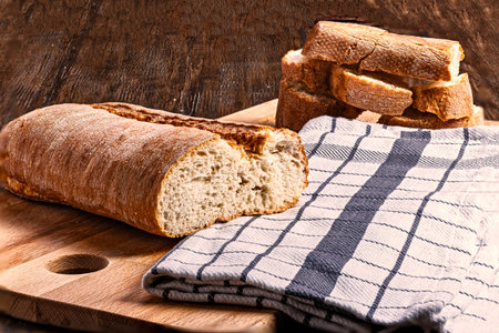 loaf of bread on cutting board and napkin on wooden background