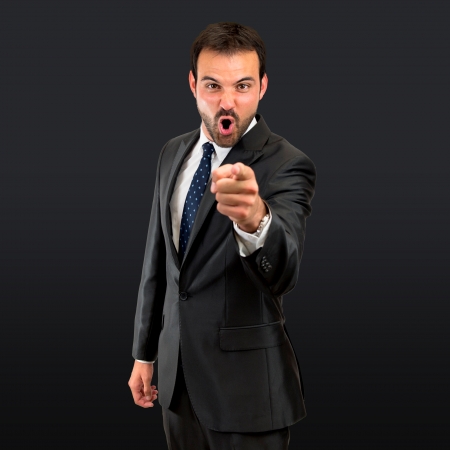 businessman angry and shouting over isolated black background の写真素材