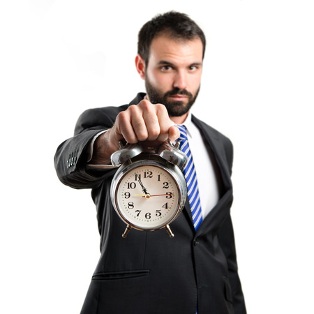 Young businessman holding an antique clock over white backgroundの写真素材