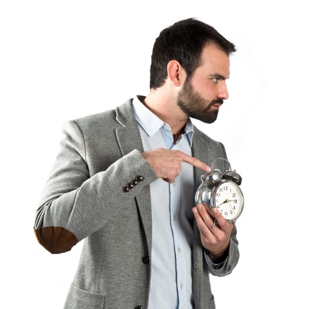 Young businessman holding an antique clock over white background の写真素材