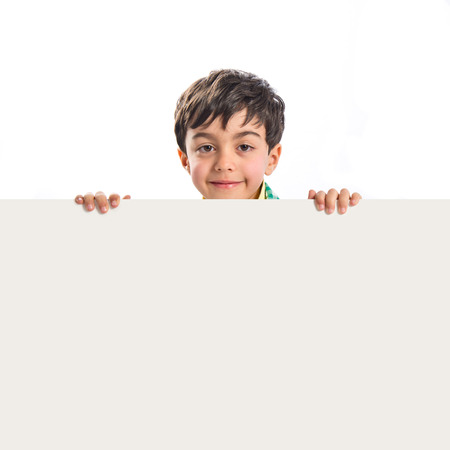 Kid holding empty placard over white background の写真素材