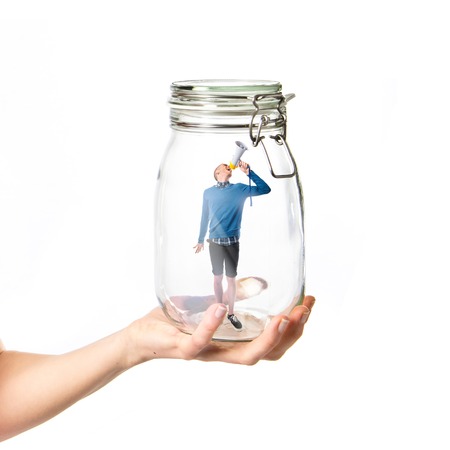 Man shouting by megaphone inside glass jarの写真素材