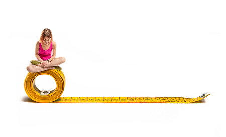 Young pretty girl looking down on tape measureの写真素材