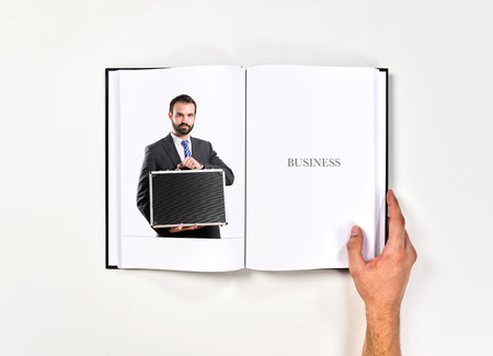 Young businessman with his briefcase printed on bookの写真素材