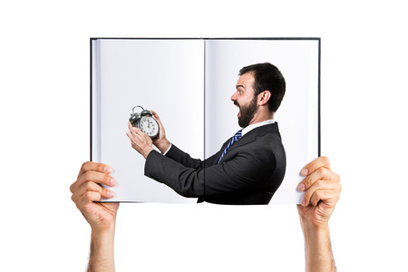 Young businessman holding an antique clock printed on bookの写真素材