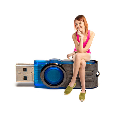 Redhead girl sitting on pendrive over white background の写真素材