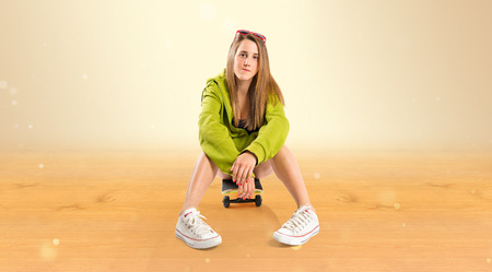 Blonde girl with skate over ocher backgroundの写真素材