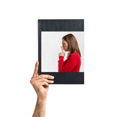 Young girl making silence gesture printed on bookの写真素材