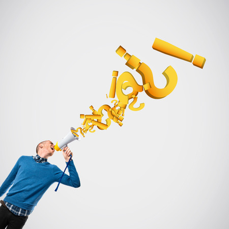 Redhead man shouting by megaphone over grey background の写真素材