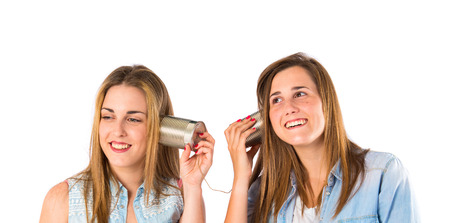 Friends talking through a tin phone over white backgroundの写真素材
