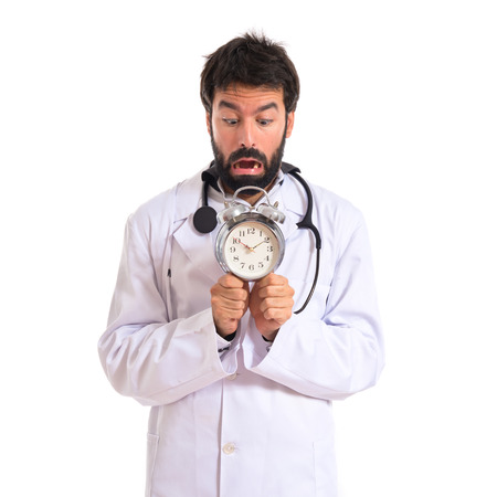 Frightened doctor holding a clockの写真素材