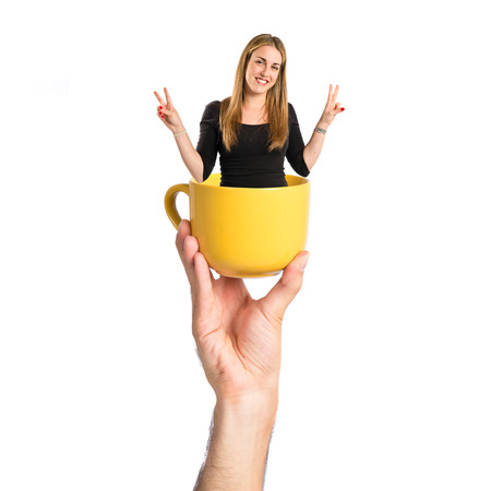 Blonde girl doing victory gesture inisde cup of coffeeの写真素材