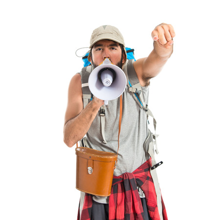 Backpacker shouting by megaphone over white backgroundの写真素材