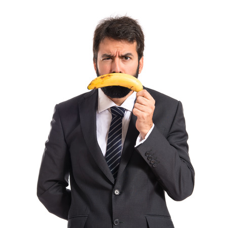 Sad businessman with banana over white backgroundの写真素材