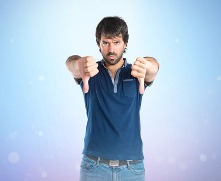 Man doing a bad signal over blue の写真素材