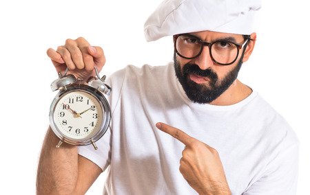 Chef holding a clock over white の写真素材