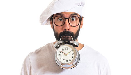 Crazy chef holding a clock over white の写真素材
