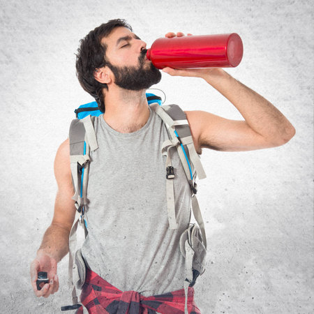 Backpacker drinking water over white backgroundの写真素材