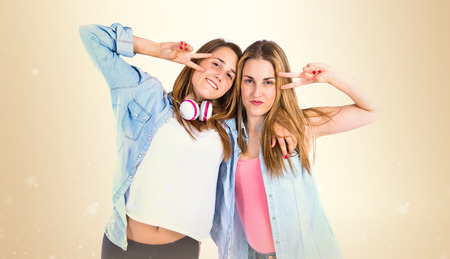 Friends doing victory gesture over white backgroundの写真素材