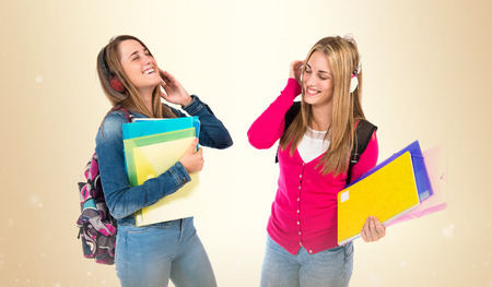 Students listening music over white backgroundの写真素材