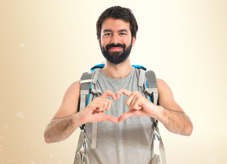 Backpacker making a heart with her hands over white backgroundの写真素材