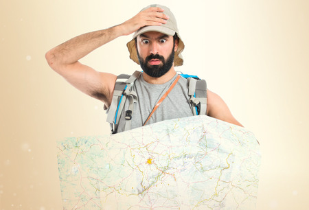 Surprised backpacker with map over white backgroundの写真素材