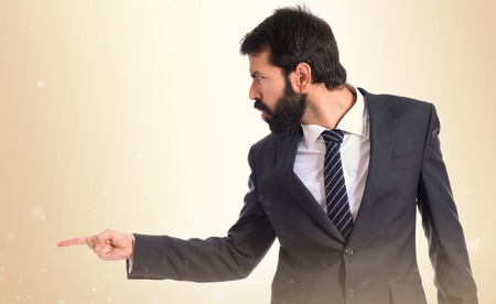 Businessman pointing and shouting over isolated white backgroundの写真素材