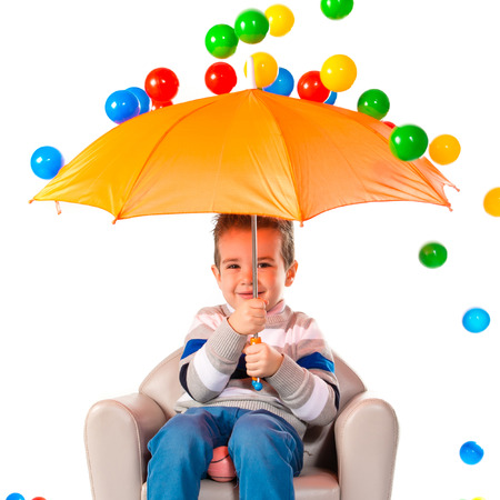 Kid holding an umbrella around colorful ballsの写真素材