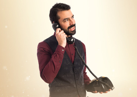 Man wearing waistcoat talking to vintage phoneの写真素材