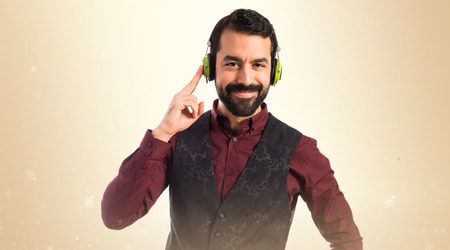 Man wearing waistcoat listening music over white backgroundの写真素材
