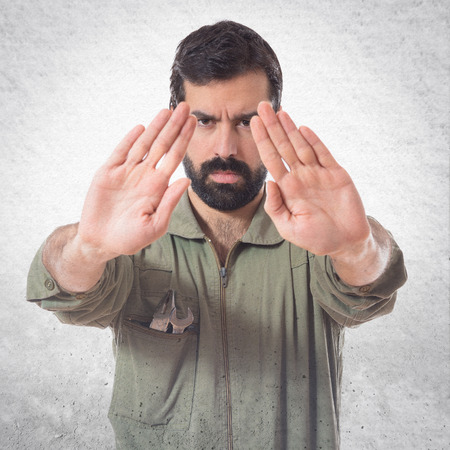 Mechanic making stop sign over white backgroundの写真素材