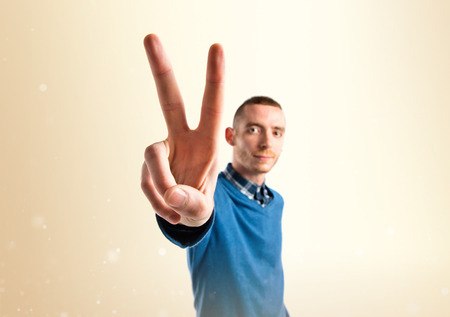 Man making victory gesture over isolated white backgroundの写真素材